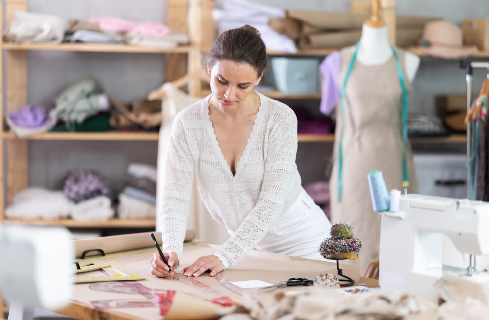 Woman tailor draw dress pattern of product on paper