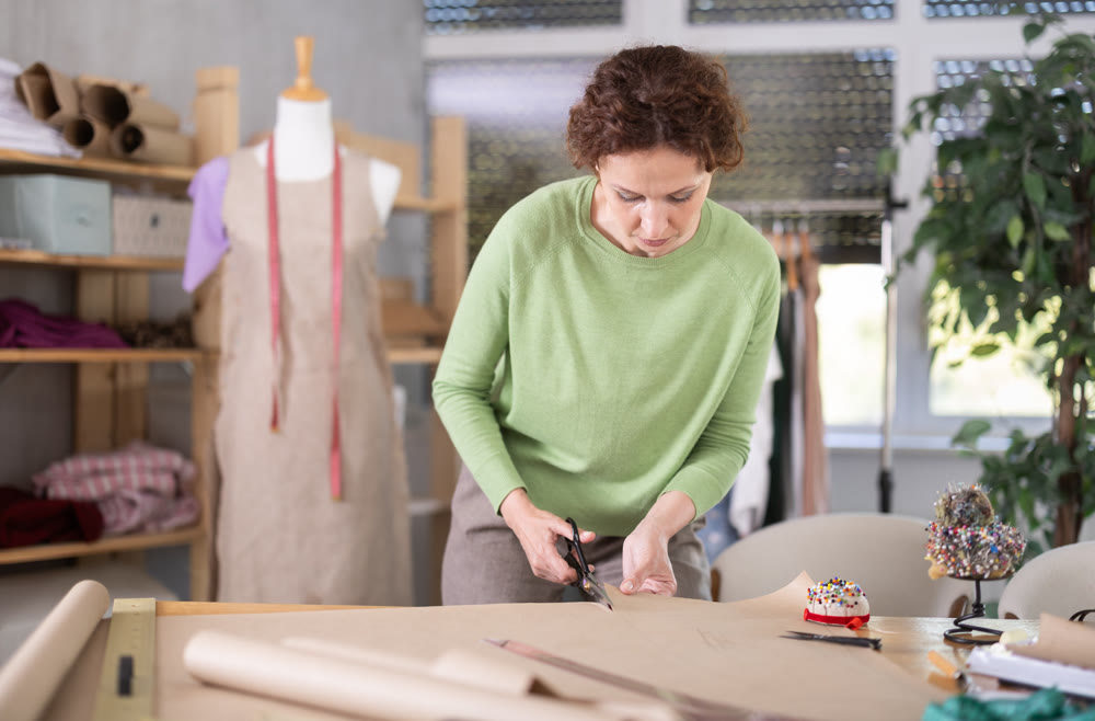 Woman tailor cuts out paper dress pattern