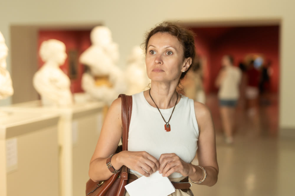 Woman looks at museum sculptures with brochure