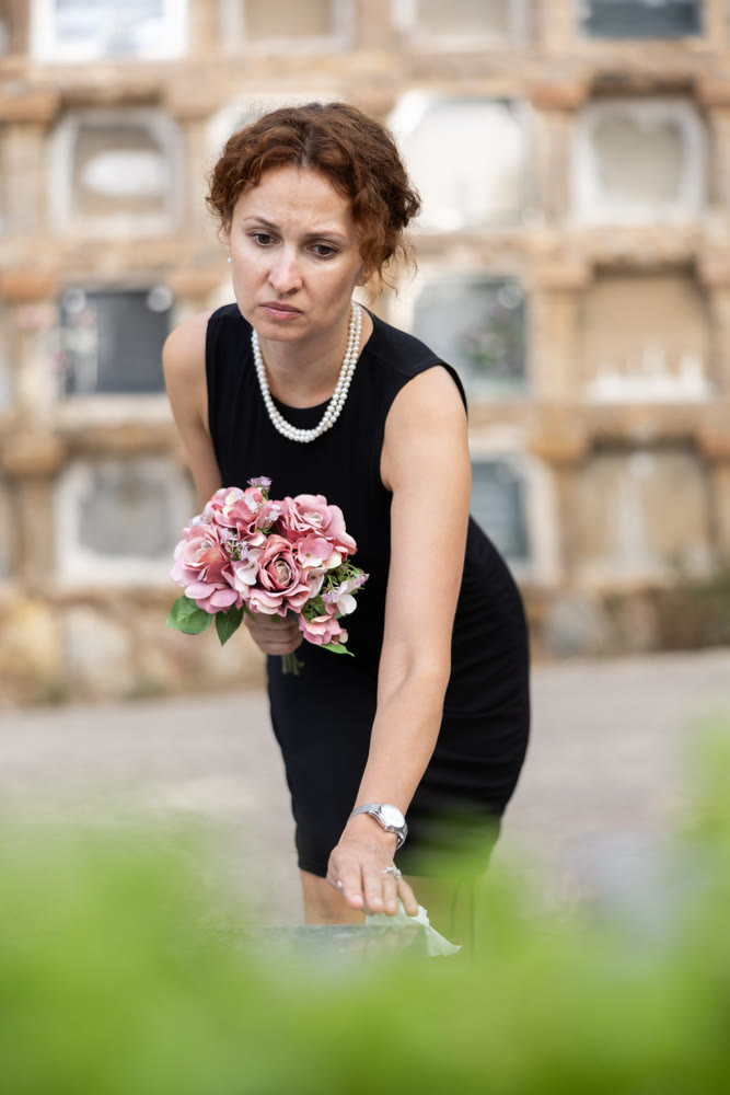 Woman in black dress came to cemetery to lay flowers on grave