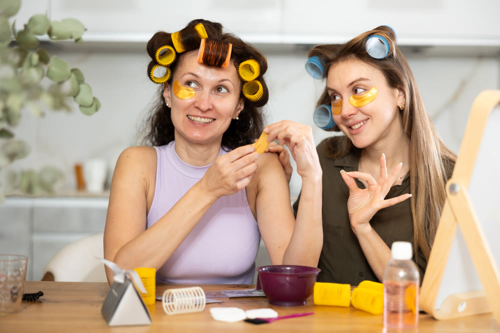 Female friends in colorful rollers applying golden under-eye patches