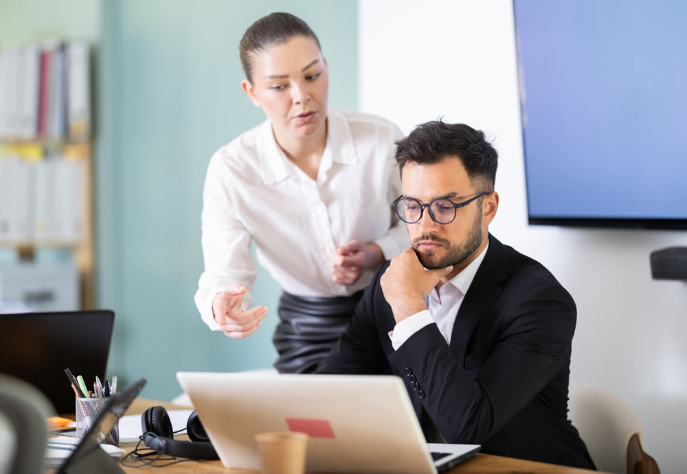 Man works at laptop and demonstrates project to girl colleague