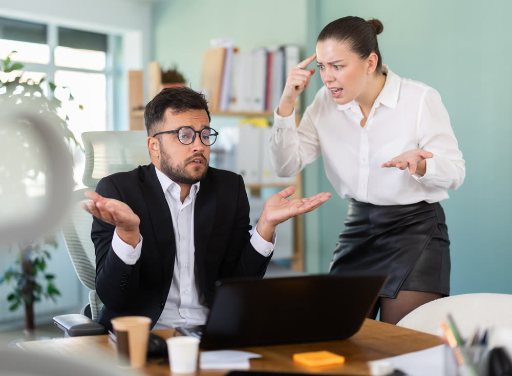 Female boss yells at man employee, man work at computer and reprimanded by management