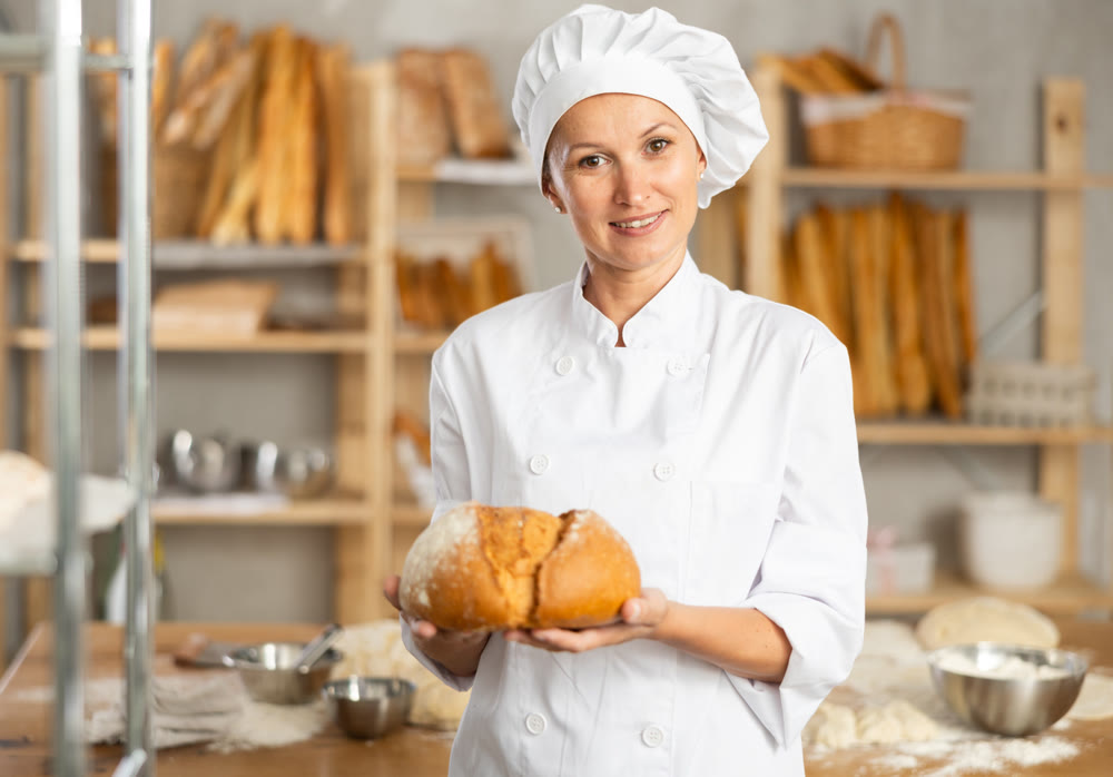 Female baker worker show loafs of breads