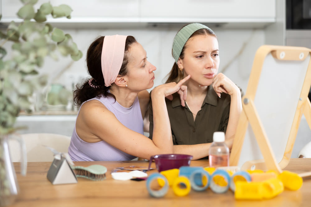 Two women looking at themselves in mirror
