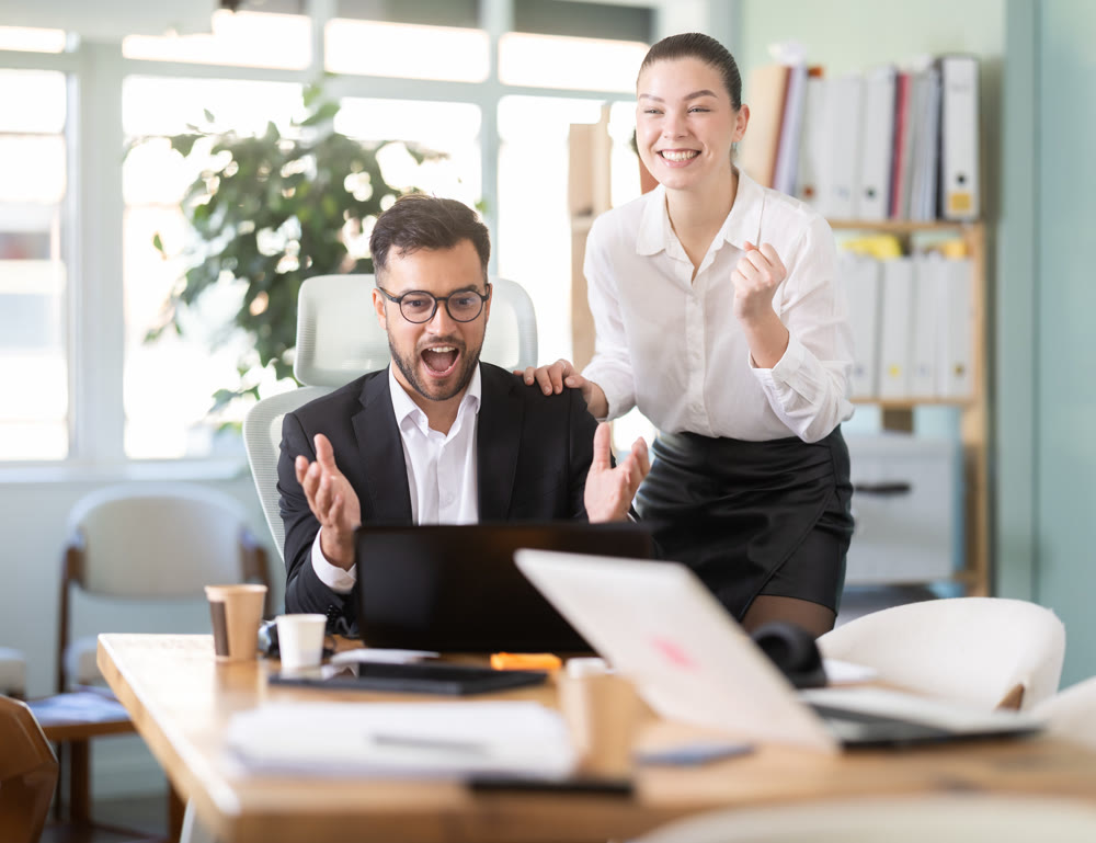 Man and a woman work in an office and are emotionally joy about the success in a new project