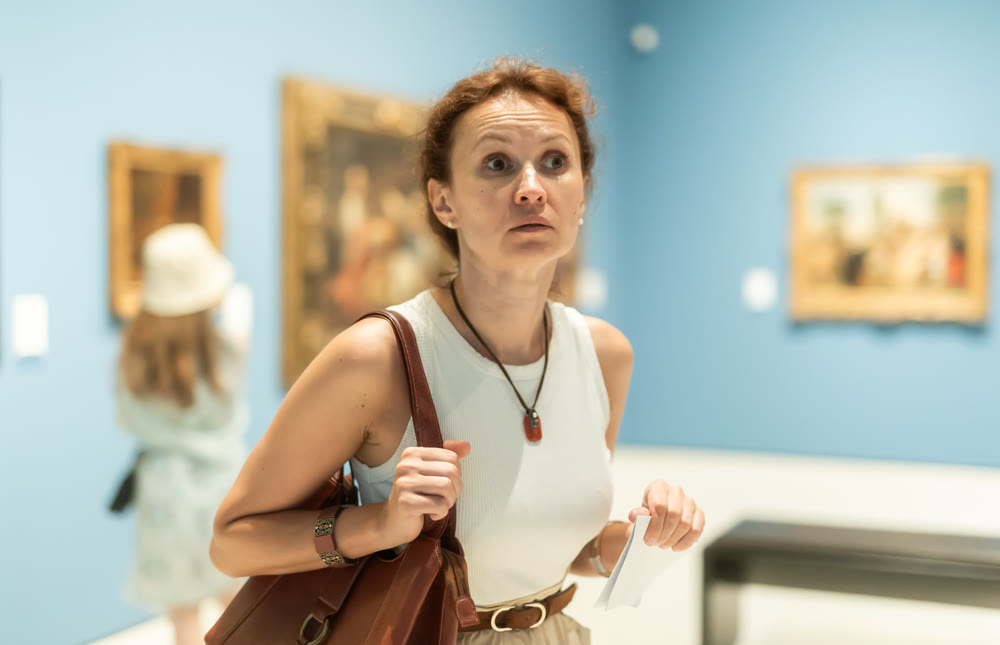 Thoughtful attentive woman standing in front of painting in art museum