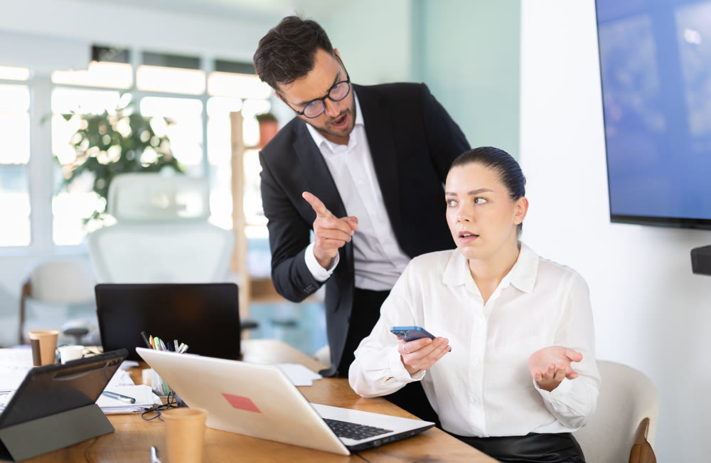 Male boss chastises girl subordinate for idleness and scrolling of phone