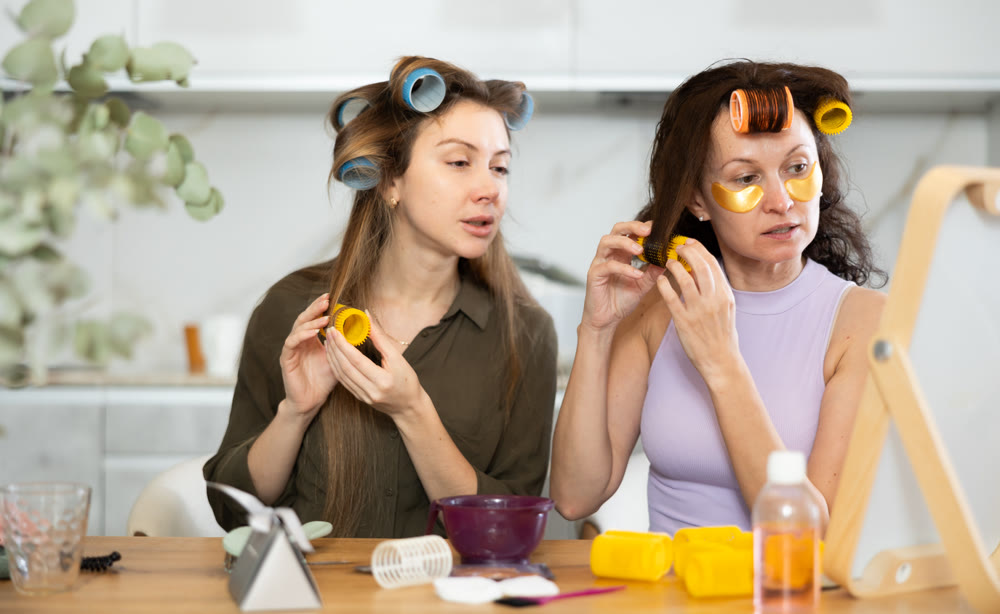 Two women curling their hair with curlers