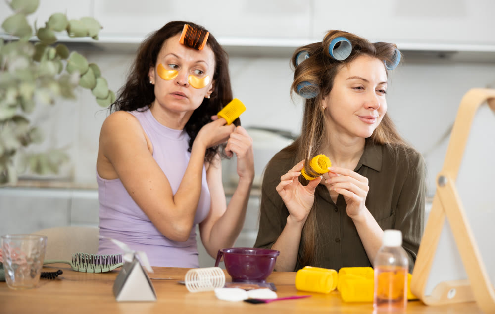 Two women curling their hair with curlers