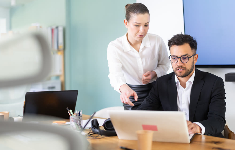 Woman help an male manager learn to use laptop