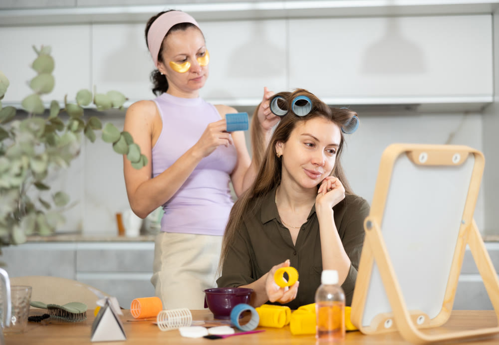 Adult woman curls hair of young woman