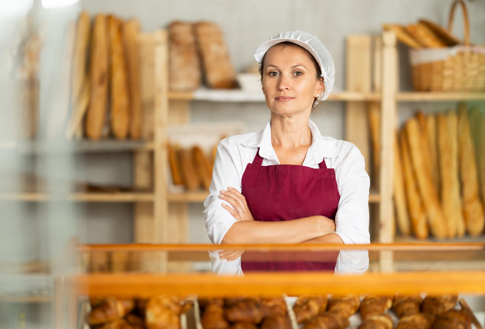Portrait of professional female baker in uniform in bakery
