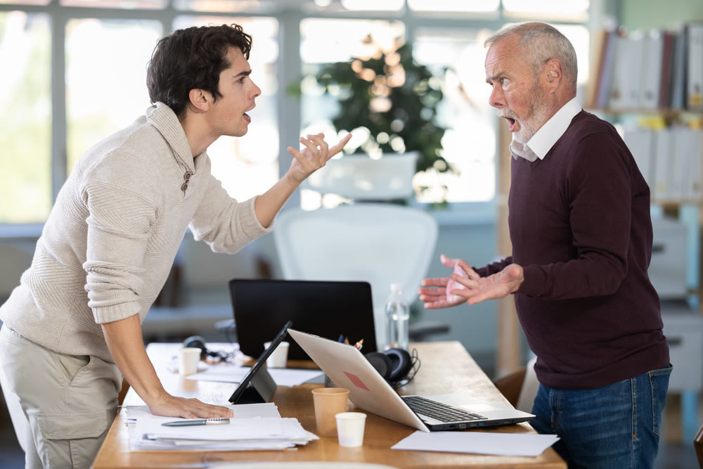 Elderly and young male colleague are arguing excitedly in office