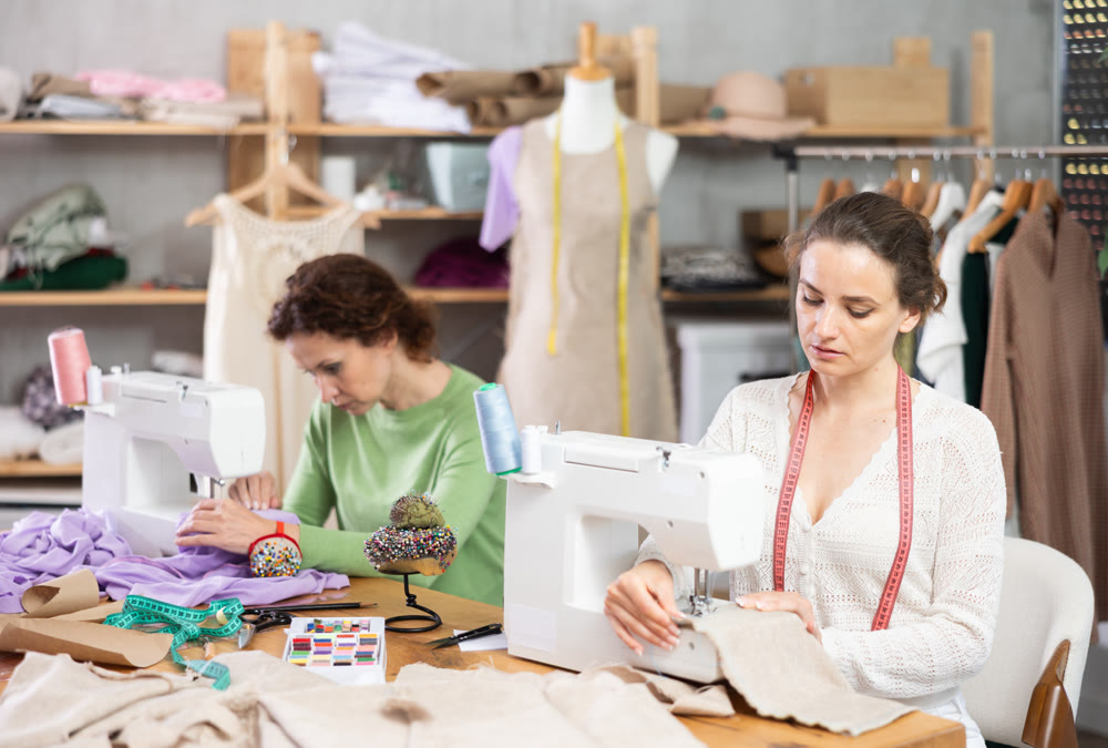 Working in sewing workshop - two woman working at sewing machines, creating clothes