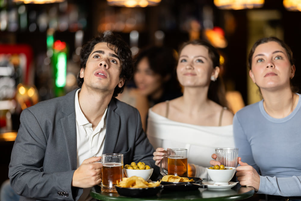Group of friends watching sports match at bar