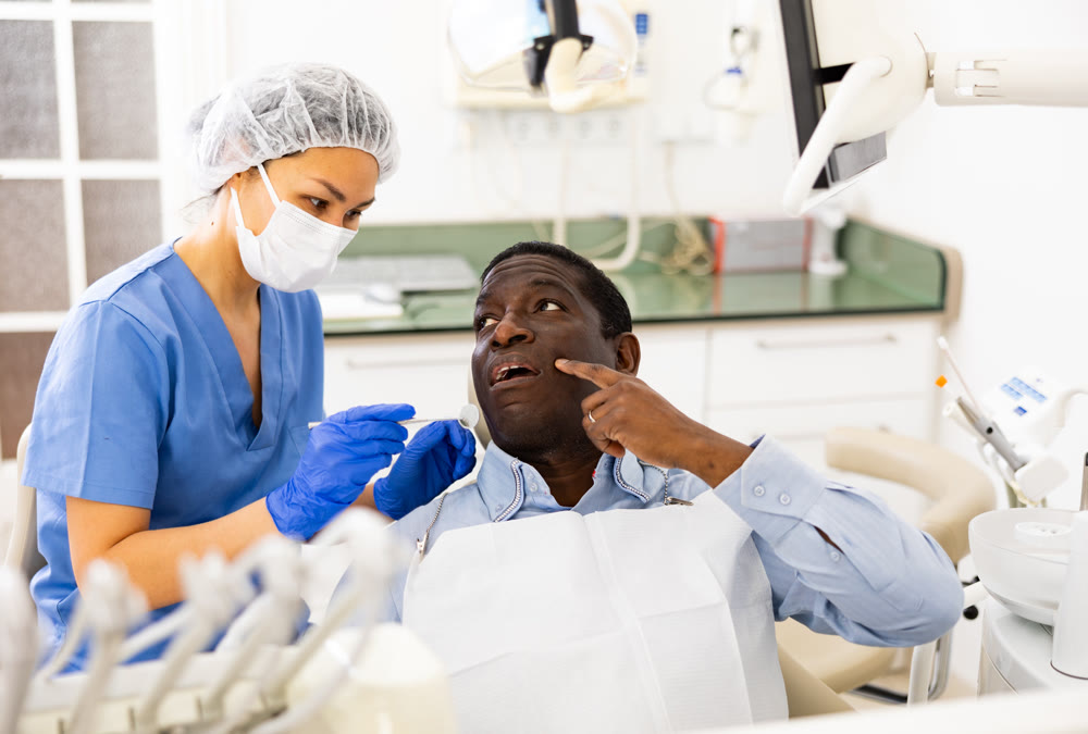 Patient pointing at tooth with problem during consultation in dental clinic