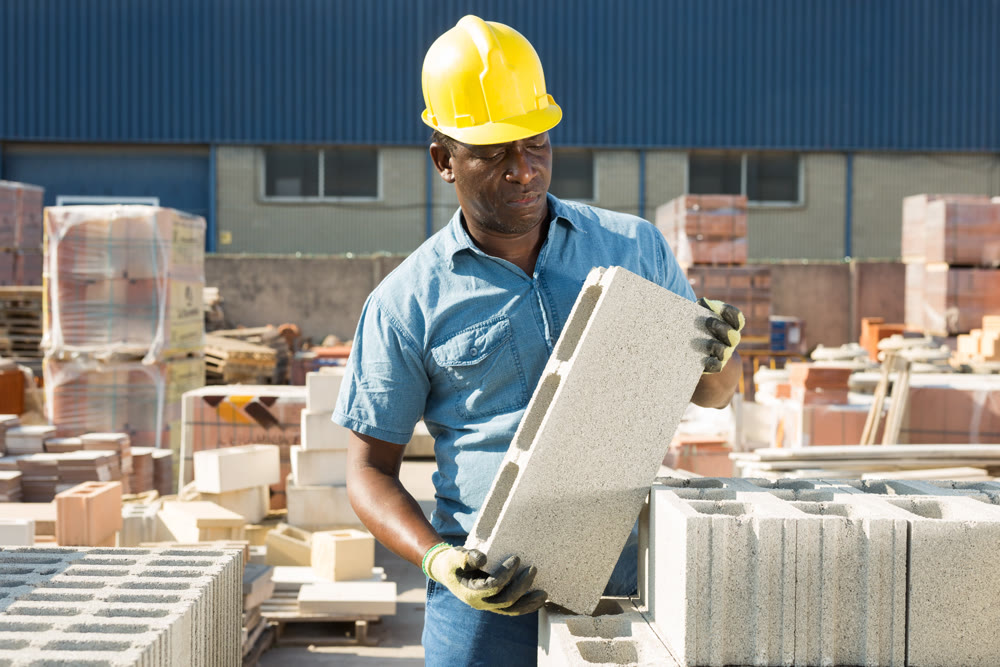 Man holding hollow concrete brick in hands in outdoor warehouse