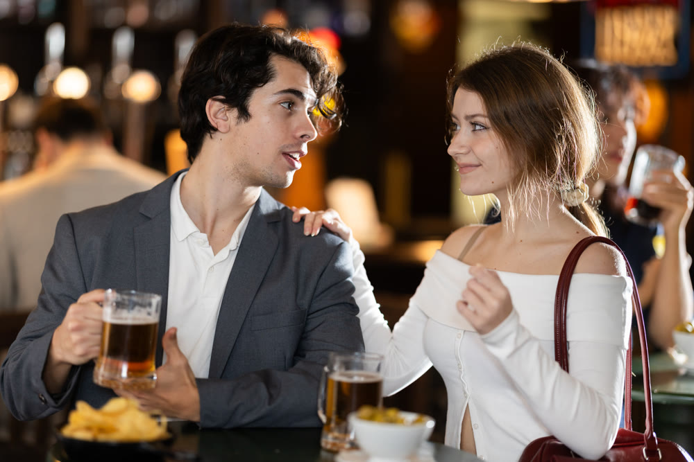 Young couple sitting at bar table drinking beer and talking