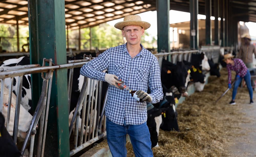 Male farmer standing with syringe at farm