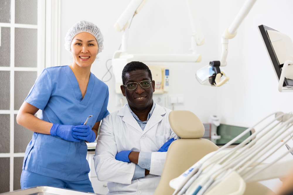 Positive confident dentist with female assistant in dental office