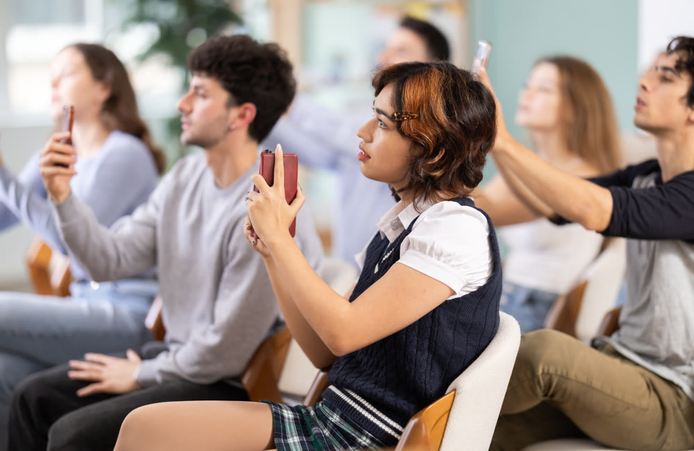 Young girl using mobile phones to scan QR code during interactive lesson