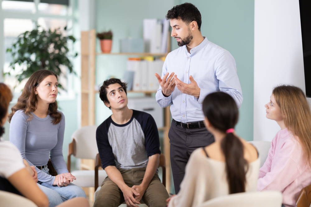 Male teacher talking to interested students sitting in a circle