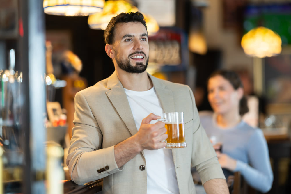 Young man drinks beer and watches match at bar