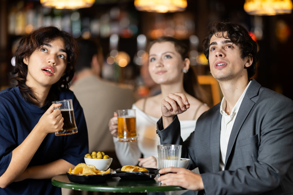 Group of friends hangs out at sports bar, watching teams match