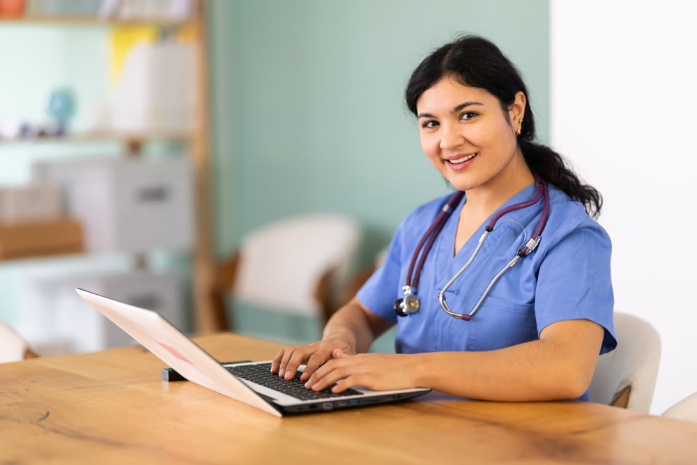 Female doctor works on laptop in room