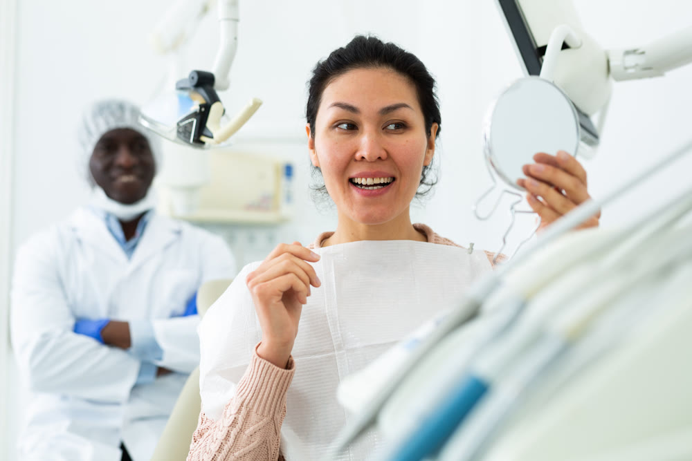 Female patient satisfied after dental treatment in dentist office