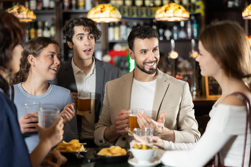 Group of friends at bar talking and drinking beer