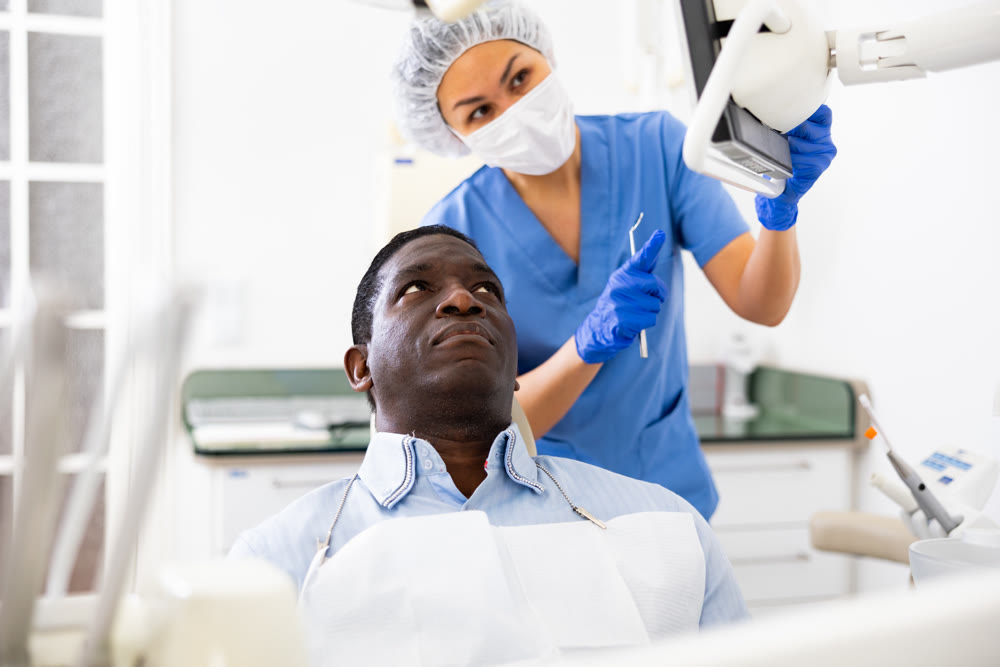 Man patient and woman dentist looking at monitor during consultation