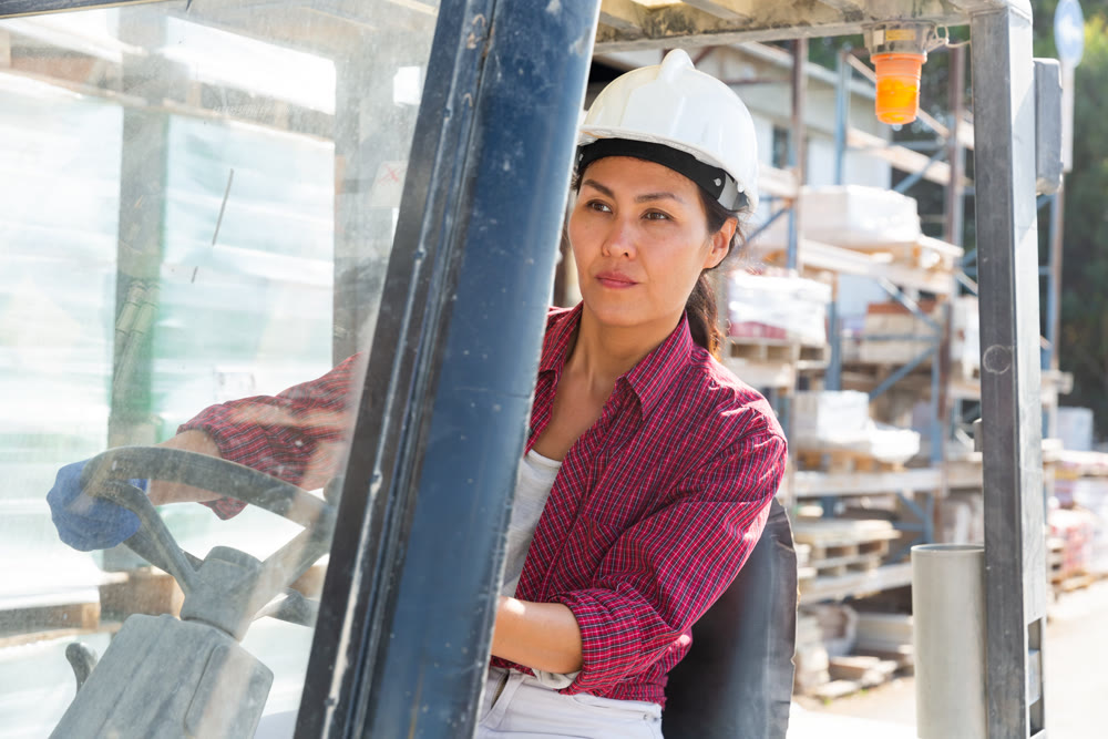 Asian woman working on forklift at construction store