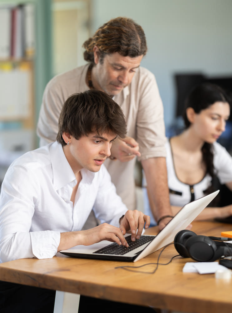 Man helps guy complete task on laptop