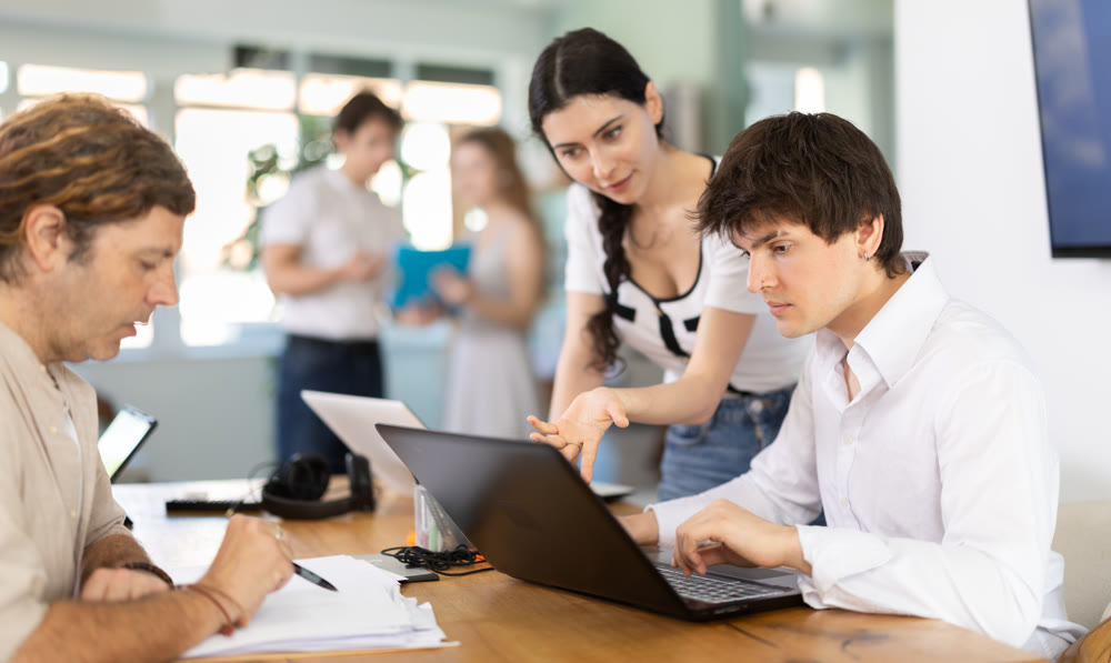 Employees working with laptops and paper documents in office