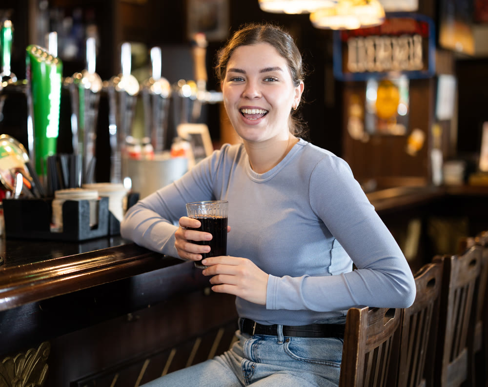 Portrait of an attractive woman with glass of cocktail at bar counter