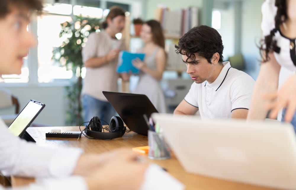 Employees working with laptops and paper documents in office