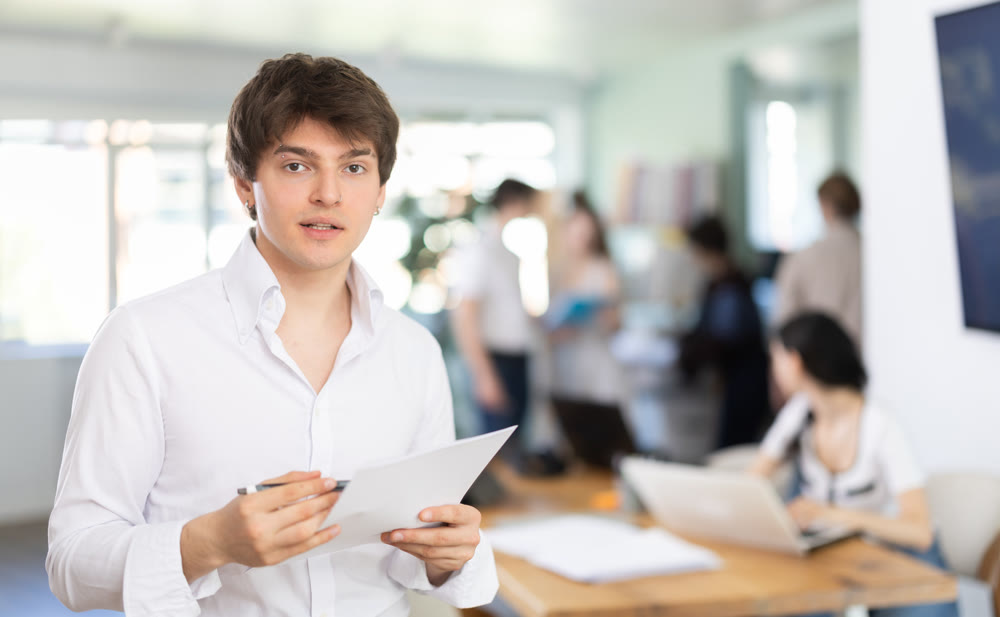 Young man standing in office with paper documents