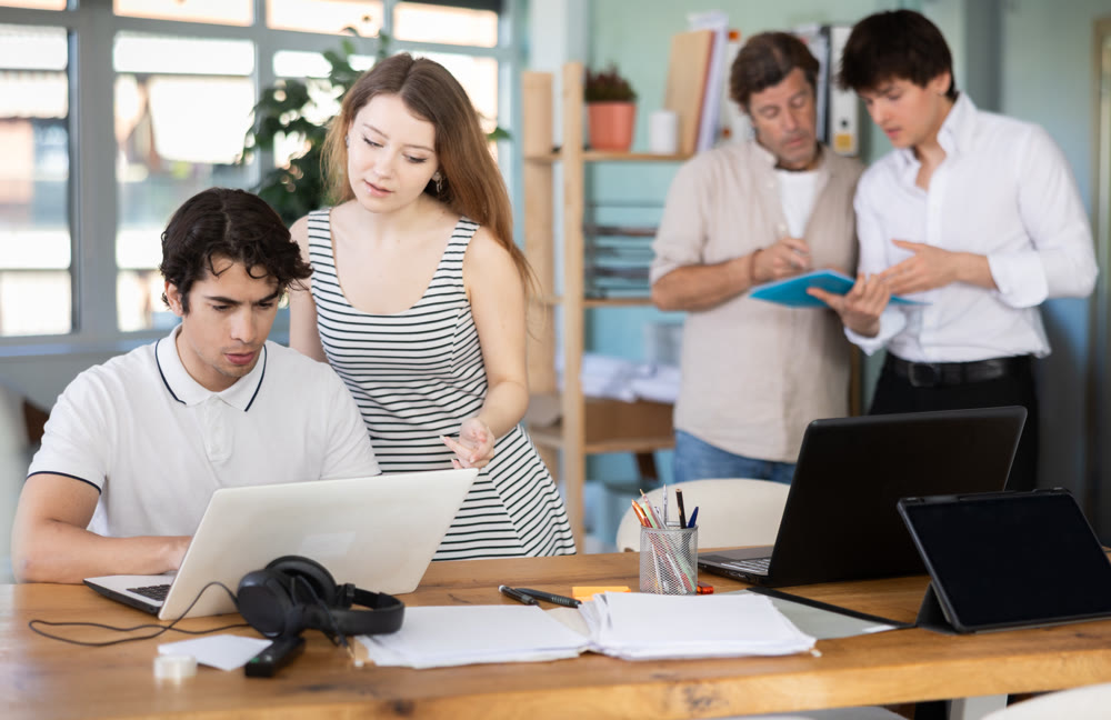 Employees working with laptops and paper documents in office