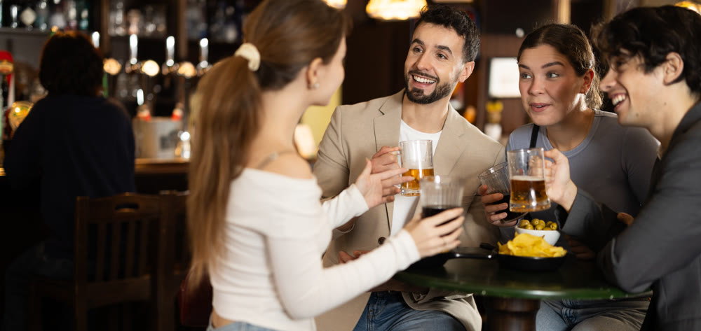 Group of happy friends in bar, drinking beer and having conversation