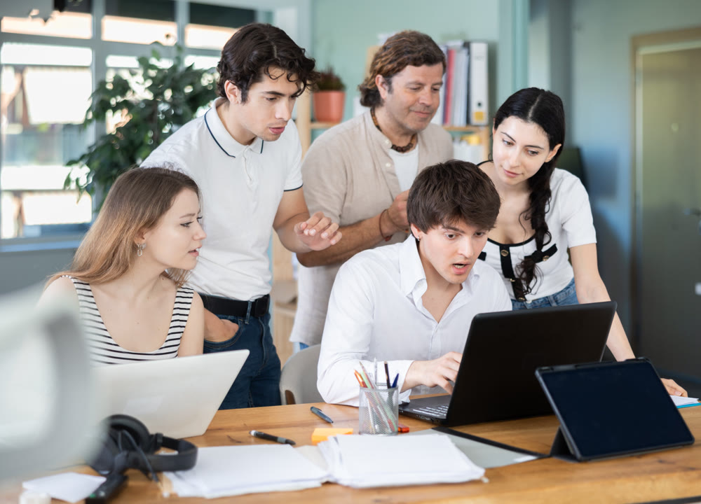 Colleagues looking at one laptop together in office