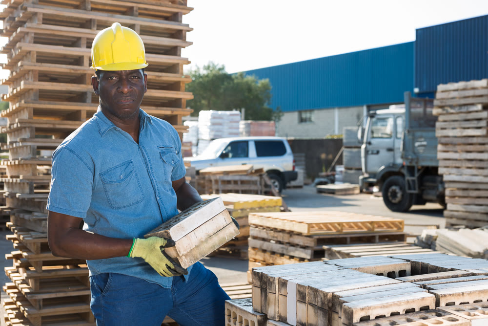 Man carrying hollow concrete blocks outdoors