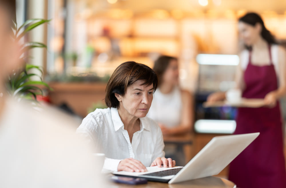 Elderly woman with laptop in cafe