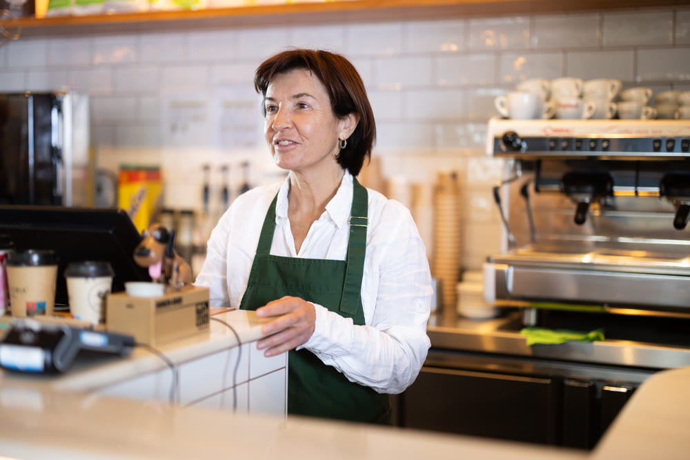 Senior woman salesperson works in cafeteria bakery shop