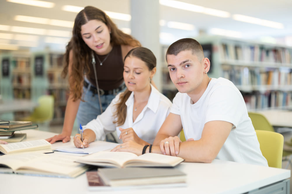 Friendly group of students prepare for classes and exams by studying together in university library