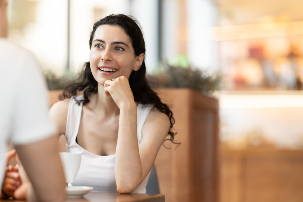 Girl in cafe sits opposite male companion, has nice conversation