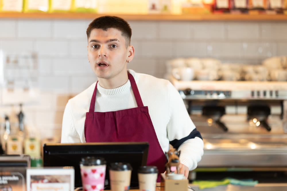 Young man at cash register in cafe