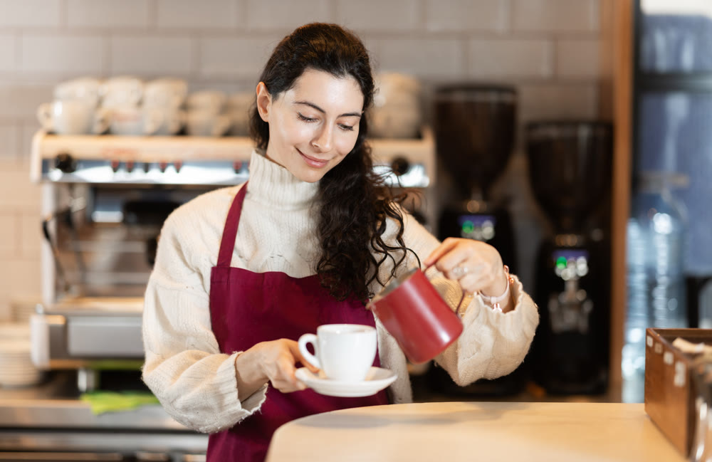Barista in red apron brewing coffee