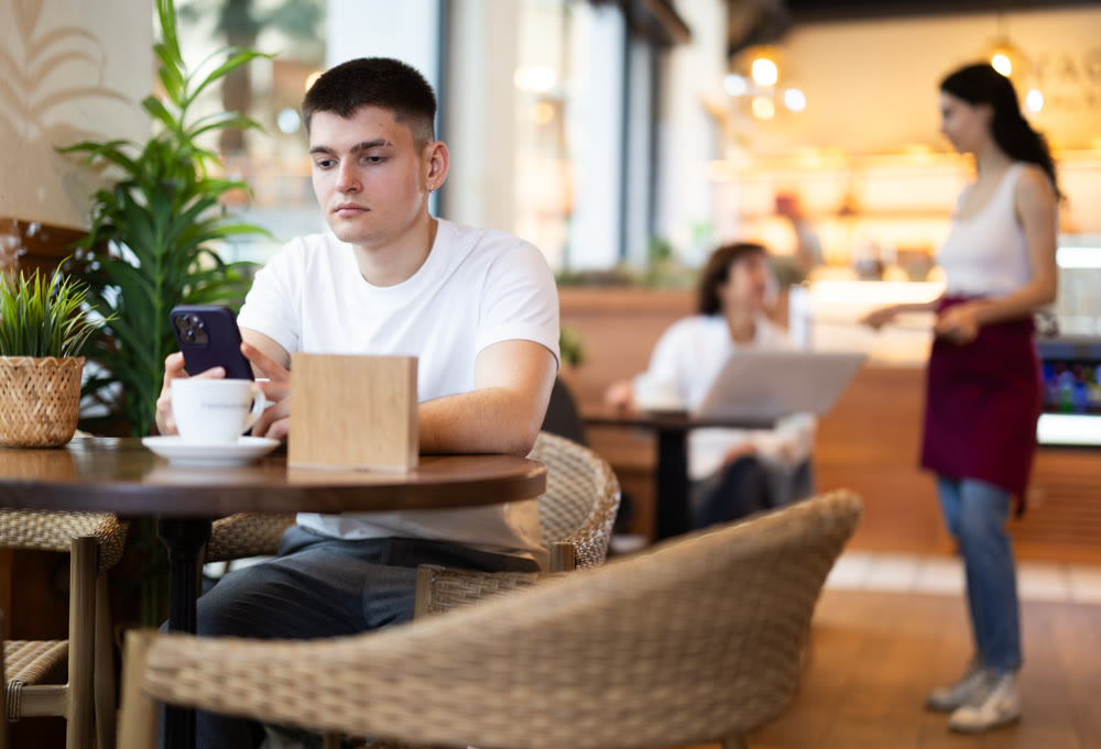 Young man with phone in cafe
